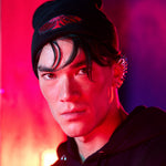 A person with dark hair and a metallic ear cuff wears the black Midnight Madness beanie and a dark hoodie, illuminated by dramatic red and purple neon lighting.