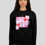 A woman modeling a black crewneck sweatshirt featuring a pink and red graphic print of the Toronto International Film Festival (TIFF) logo and building on the front, paired with blue jeans against a solid gray background.