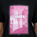 A black short-sleeve crewneck t-shirt featuring a large pink graphic print on the front with the text 'To Intl Film Fest' and a stylized Toronto skyline, worn by a model.