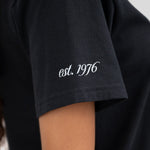 The sleeve of a t-shirt that reads est. 1976.