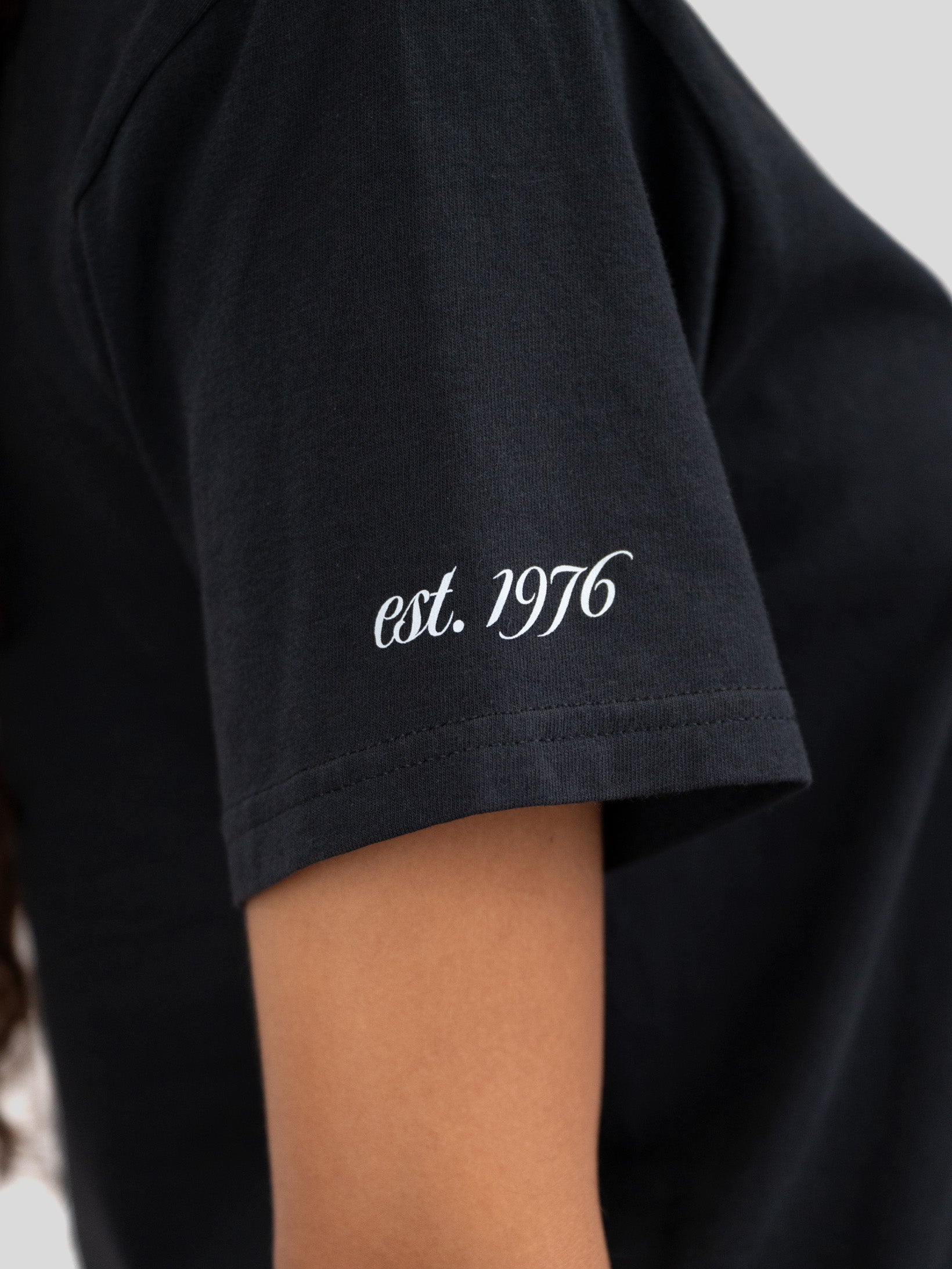 The sleeve of a t-shirt that reads est. 1976.