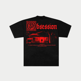 The back of the black t-shirt displays a large red graphic featuring the gothic title "Obsession" above a dark, high-contrast image of a house with a glowing red doorway and a silhouetted figure, accompanied by a dictionary definition of the word below.