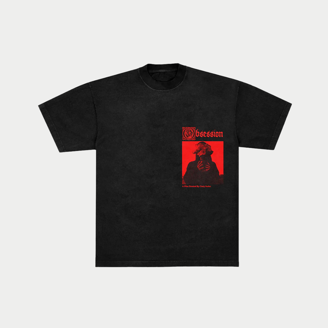 A black vintage-wash t-shirt featuring a small graphic on the left chest with a red square showing a shrouded figure holding flowers under the red gothic text "Obsession" and the credit line "A Film Directed By Curry Barker".