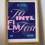 A framed art print featuring a stylized poster for the 2026 Toronto International Film Festival, displayed on a small round table against a light gray wall.