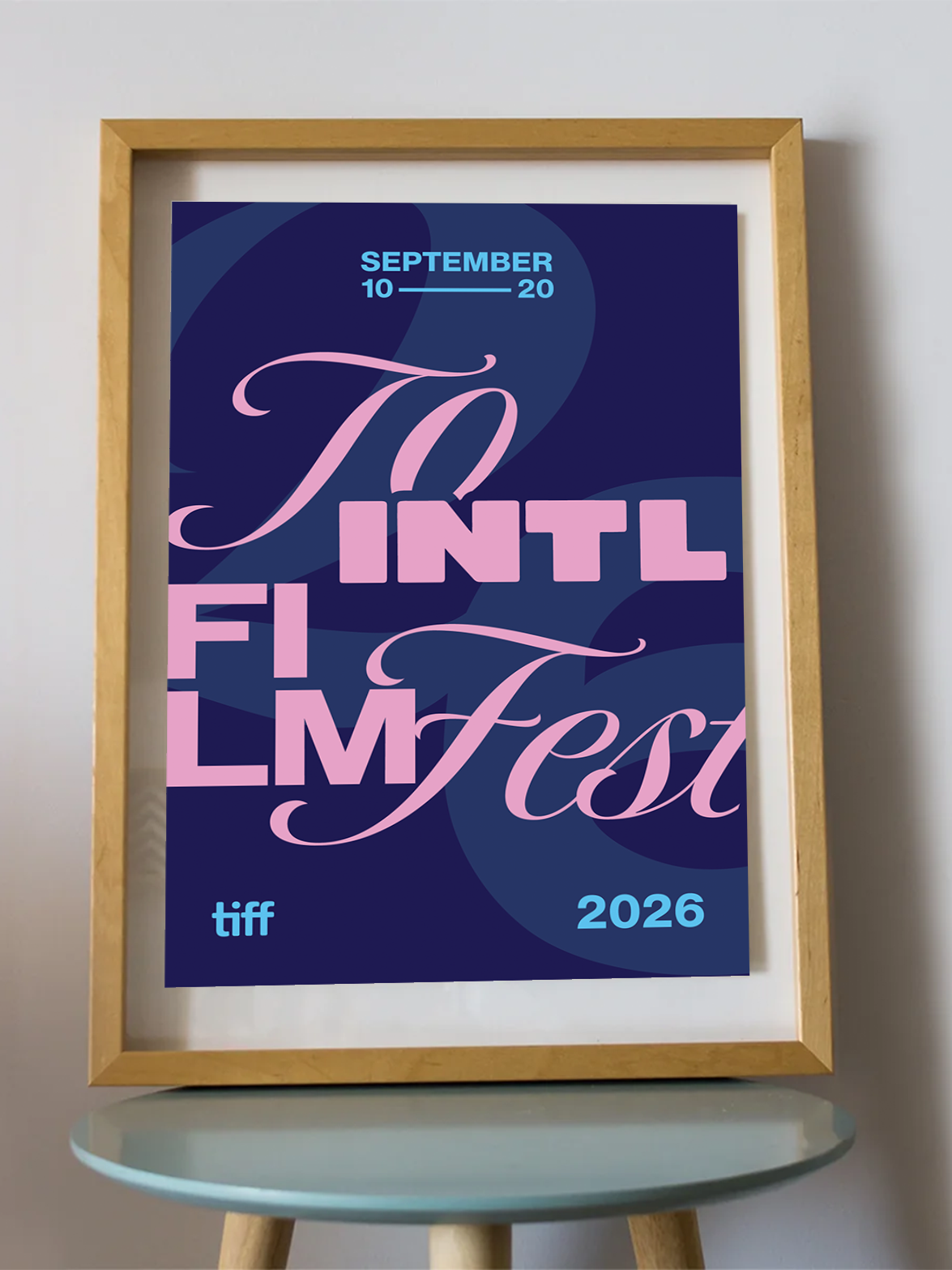 A framed art print featuring a stylized poster for the 2026 Toronto International Film Festival, displayed on a small round table against a light gray wall.