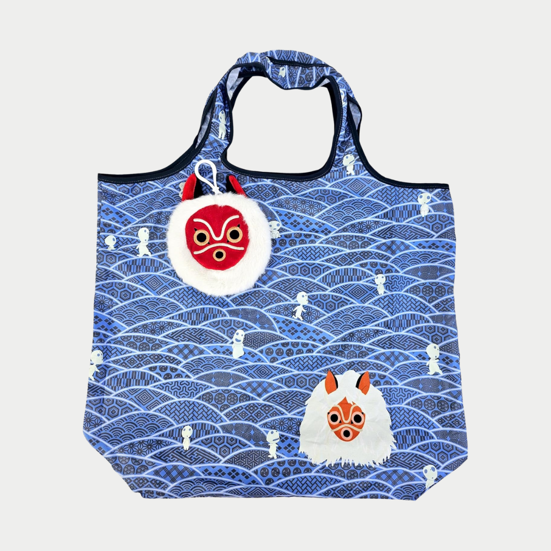 A blue reusable tote bag featuring a traditional geometric wave pattern dotted with small white Kodama spirits, an illustration of San's mask, and a matching plush mask pouch clipped to the handle.