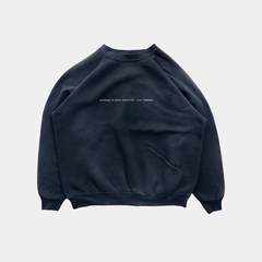 The front of a dark navy raglan-style sweatshirt featuring the lowercase phrase "nothing is more beautiful than shadows" printed in a small white typewriter font across the chest.
