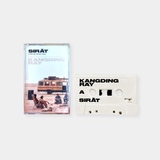 A white cassette tape and its J-card case for the original motion picture soundtrack of the film SIRĀT by Oliver Laxe, featuring music by Kangding Ray, set against a plain gray background.