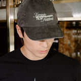 A man wearing a black t-shirt with a 'Toronto International Film Festival' graphic and a matching black baseball cap, standing in a bar environment.