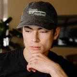 A man wearing a black t-shirt with a 'Toronto International Film Festival' graphic and a matching black baseball cap, standing in a bar environment.