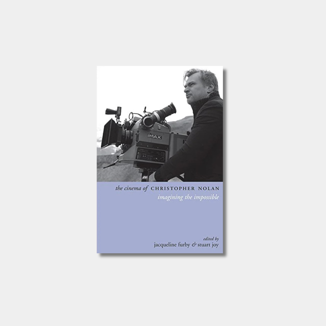A book cover for "The Cinema of Christopher Nolan: Imagining the Impossible," featuring a black-and-white photo of Christopher Nolan behind a large IMAX camera against a light blue lower section.