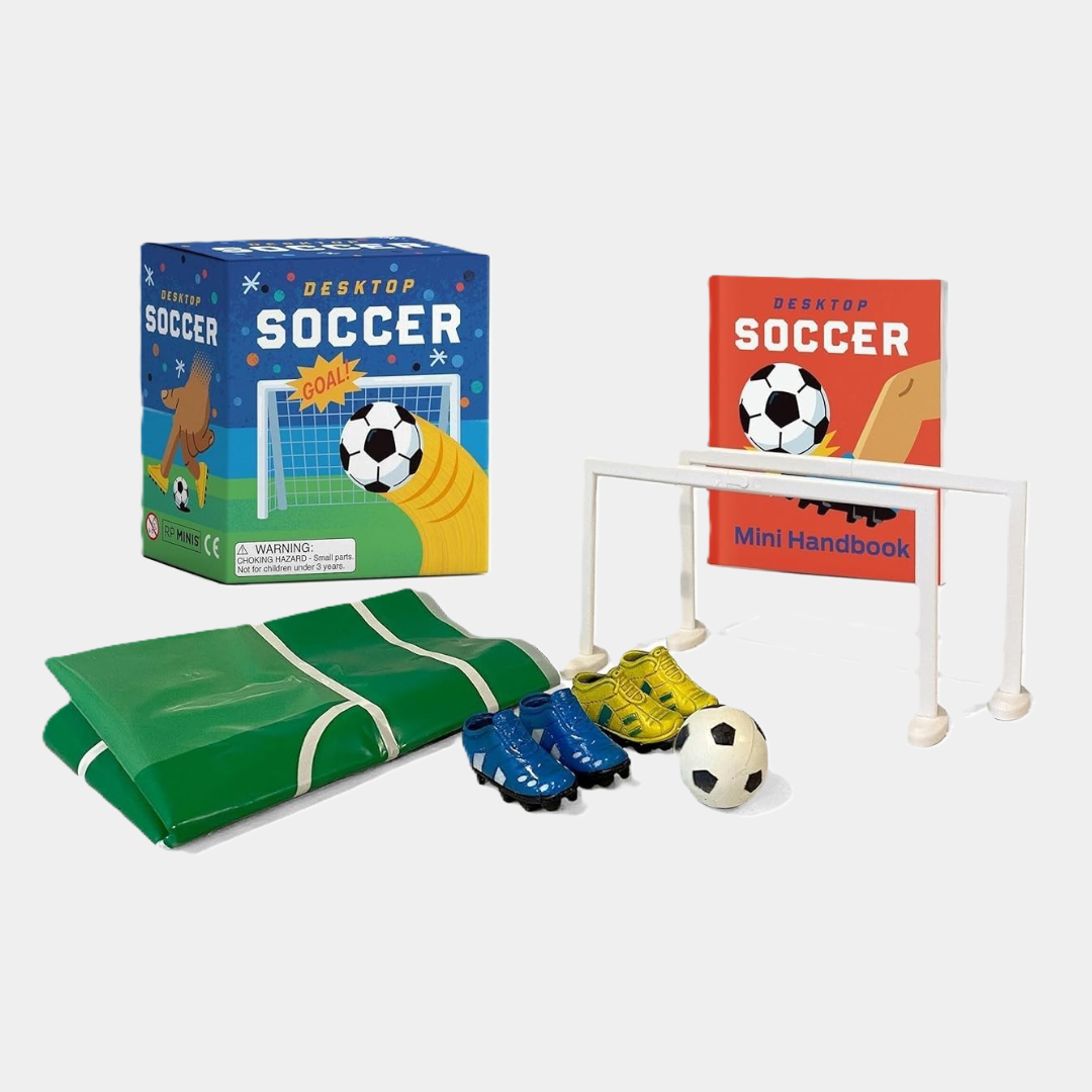Mini desktop soccer set with foldable field, goal net, ball, two pairs of cleats, and a small instruction booklet beside the product box.
