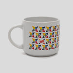 A white ceramic coffee mug featuring a repeating geometric pattern of colorful pinwheel-like shapes in yellow, orange, red, blue, and black, with a small red logo in the center.