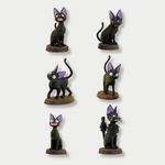 A collection of six miniature figurines displaying the black cat Jiji from Kiki's Delivery Service in various playful poses, each standing on a small brown base against a light gray background.