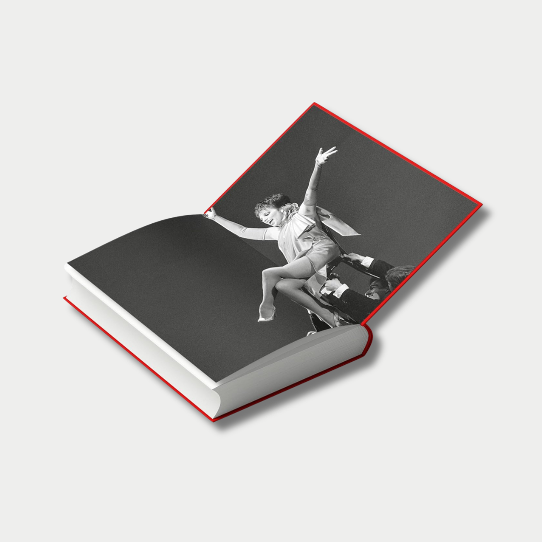 An angled view of an open hardcover book featuring a full-page, black-and-white photograph of Liza Minnelli performing with her arms outstretched as she is lifted by dancers.