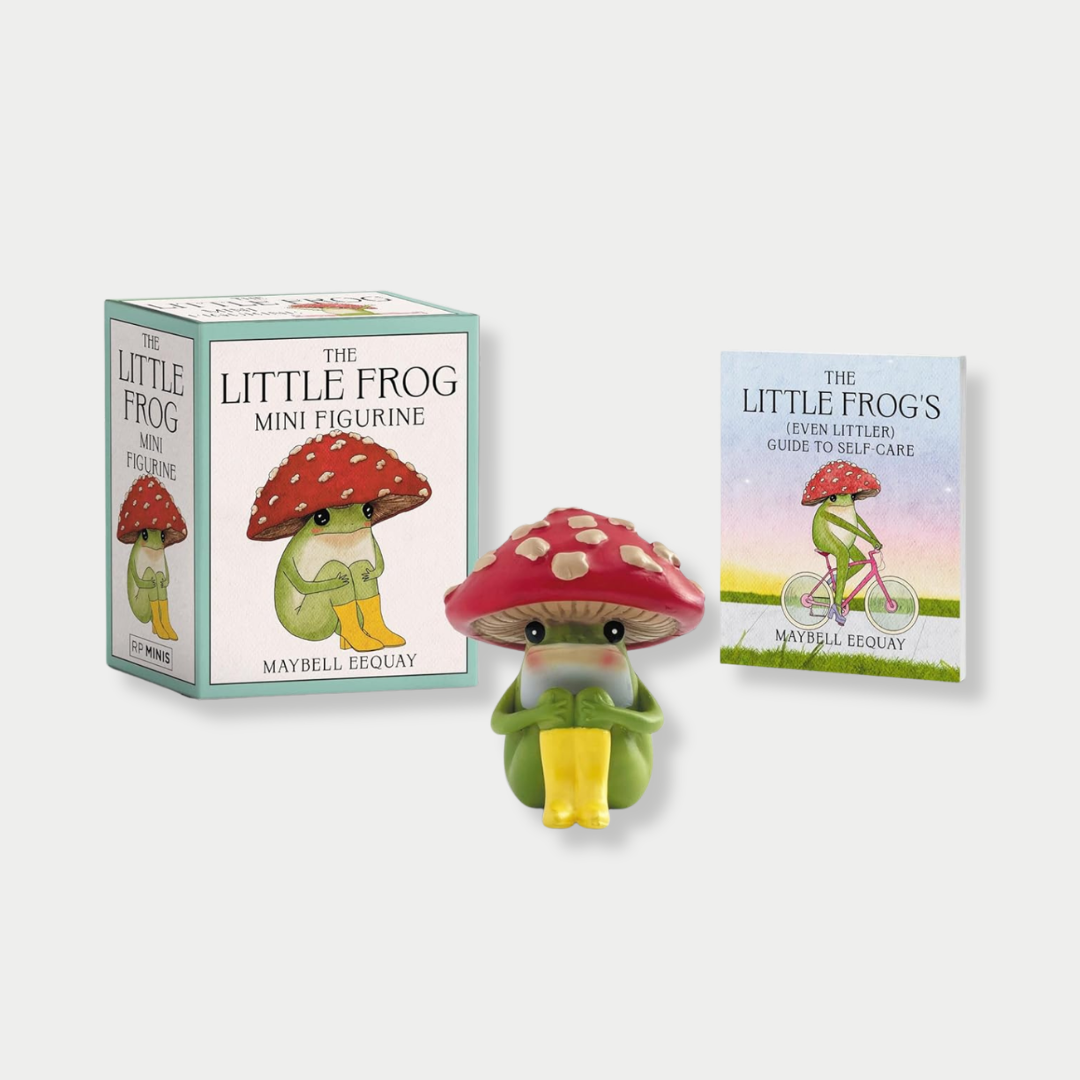 A novelty gift set featuring "The Little Frog Mini Figurine" by Maybell Eequay, displayed with its illustrated product box, a small green frog figurine wearing a red mushroom cap, and a miniature guide to self-care booklet.