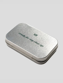 A rectangular silver metal tin with rounded corners, featuring the words 'ready for my close-up' and 'tiff' printed on the lid, set against a solid light gray background.