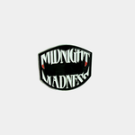 An enamel pin featuring the "Midnight Madness" logo in white, sharp-toothed lettering with blood-tipped fangs against a black, shield-shaped background.