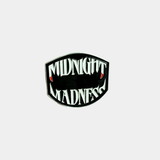 An enamel pin featuring the "Midnight Madness" logo in white, sharp-toothed lettering with blood-tipped fangs against a black, shield-shaped background.