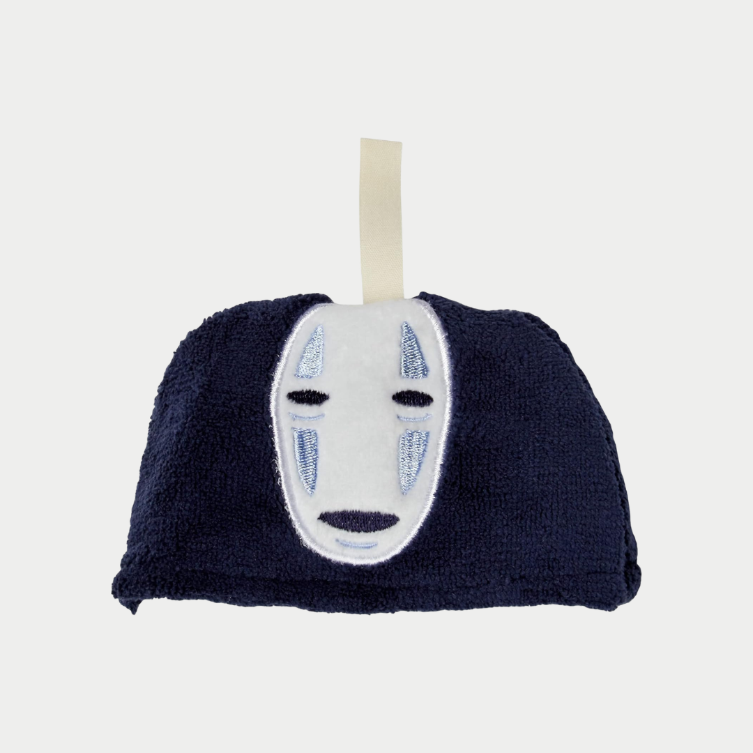 A close-up shot shows a small, dark blue plush pouch with an embroidered No-Face mask and a fabric hanging loop.