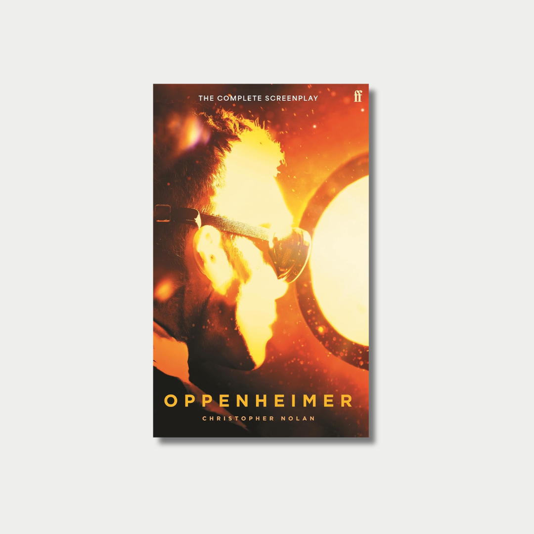 The book cover for Christopher Nolan's "Oppenheimer: The Complete Screenplay" shows the silhouette of a man wearing protective goggles as he is intensely illuminated by a fiery, golden nuclear blast, centered against a light gray background.