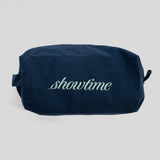 A navy blue canvas cosmetic pouch with the word 'showtime' embroidered in light green script across the front, set against a plain light gray background.