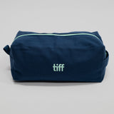 A navy blue canvas toiletry bag with a mint green zipper and a mint green 'tiff' logo on the front, photographed on a neutral light gray background.