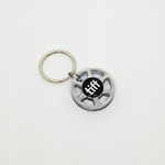Photo of a silver toned keychain that looks like a miniature film reel with the tiff logo in the centre of it.